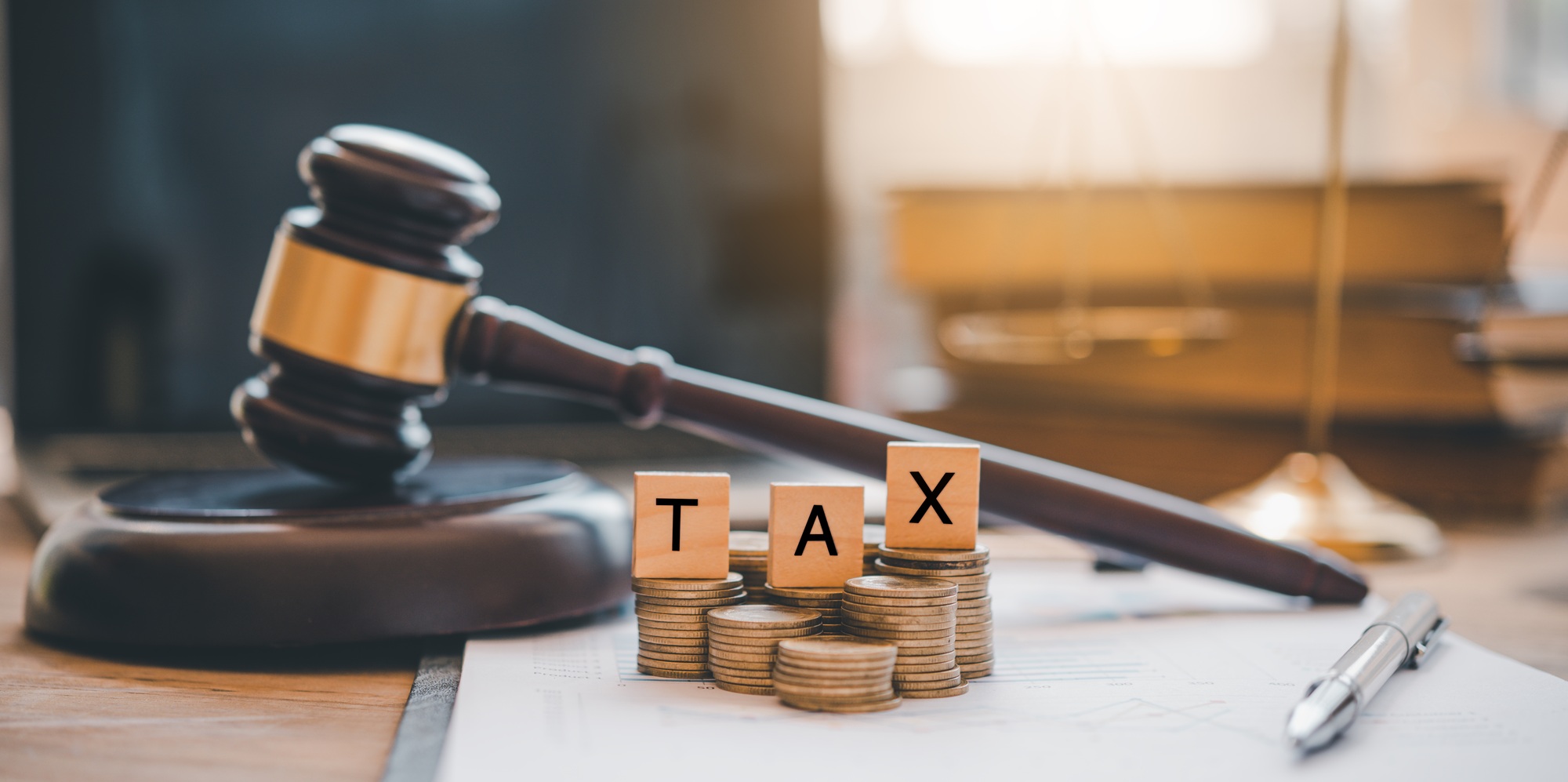 Tax law concept. Wooden blocks word " TAX" on coin stack .with gavel and money on the table.