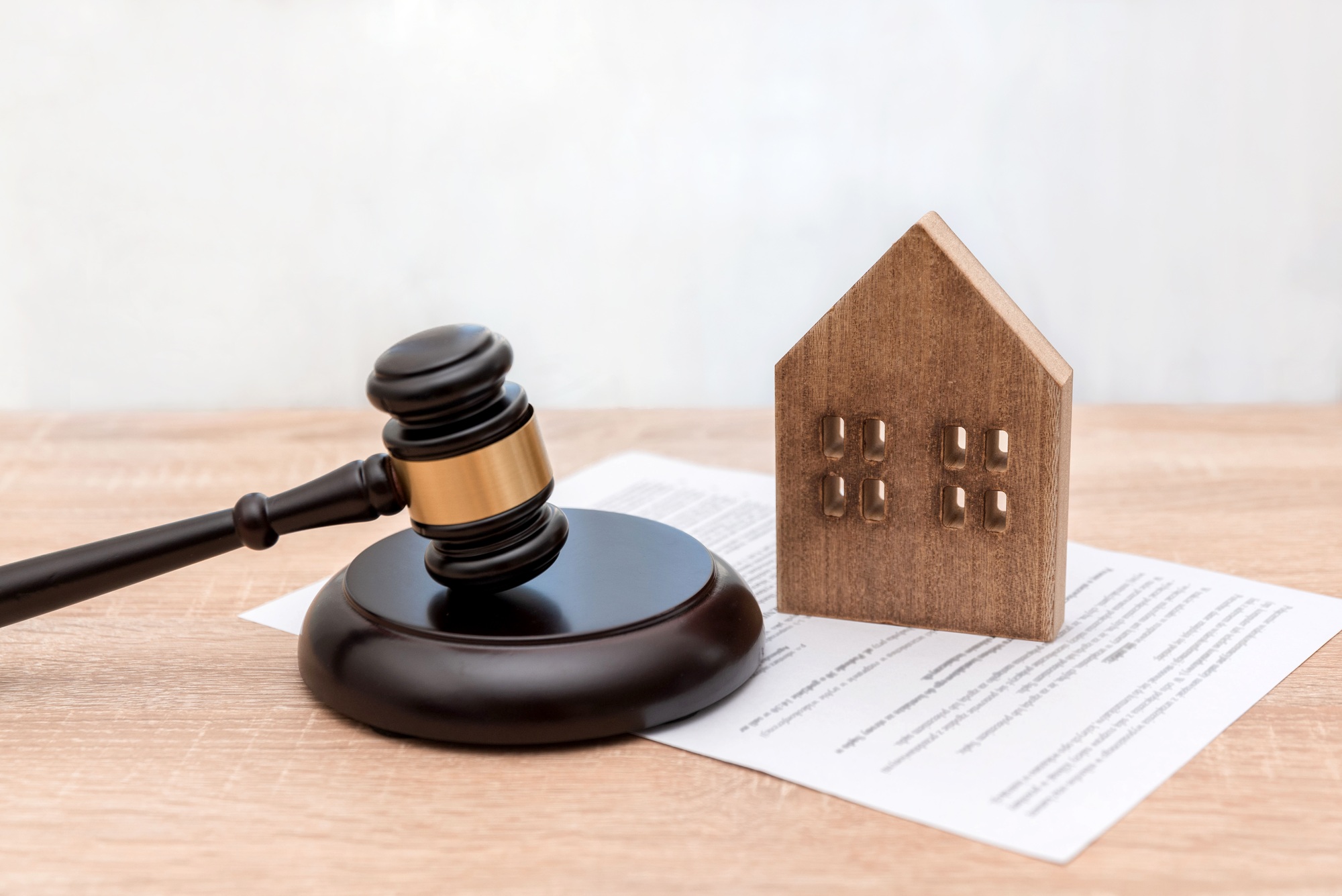 Wooden House Model with Judge's Gavel and Legal Document on Table, real estate law